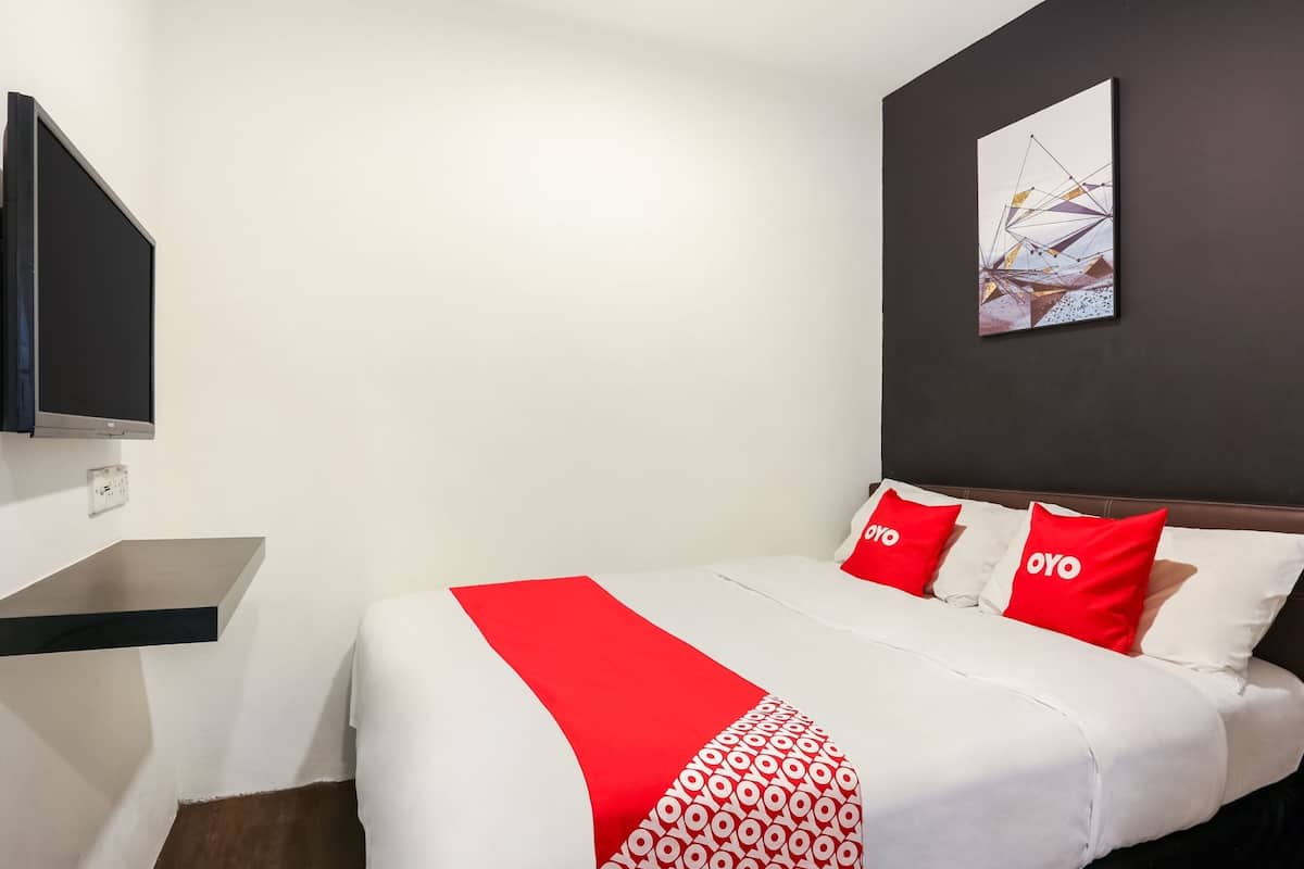 A hotel room with a bed, a flat-screen TV mounted on the wall, and a painting above the bed.