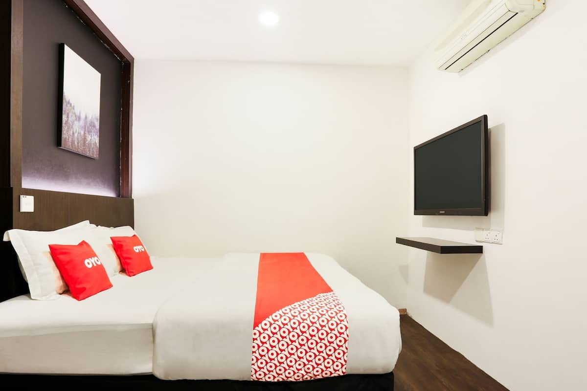 A hotel room with a bed, a TV, and a wall-mounted shelf.