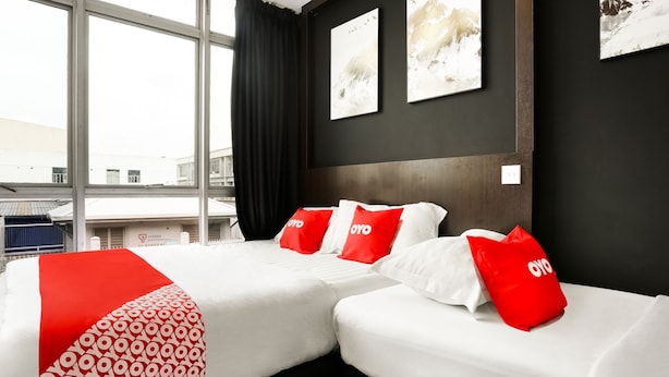 A hotel room with two beds, a large window, and artwork on the walls.