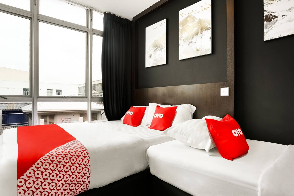 A hotel room with two beds, a large window, and artwork on the walls.
