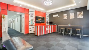 A reception area with a red and white striped counter, a bench, and a bar with stools.