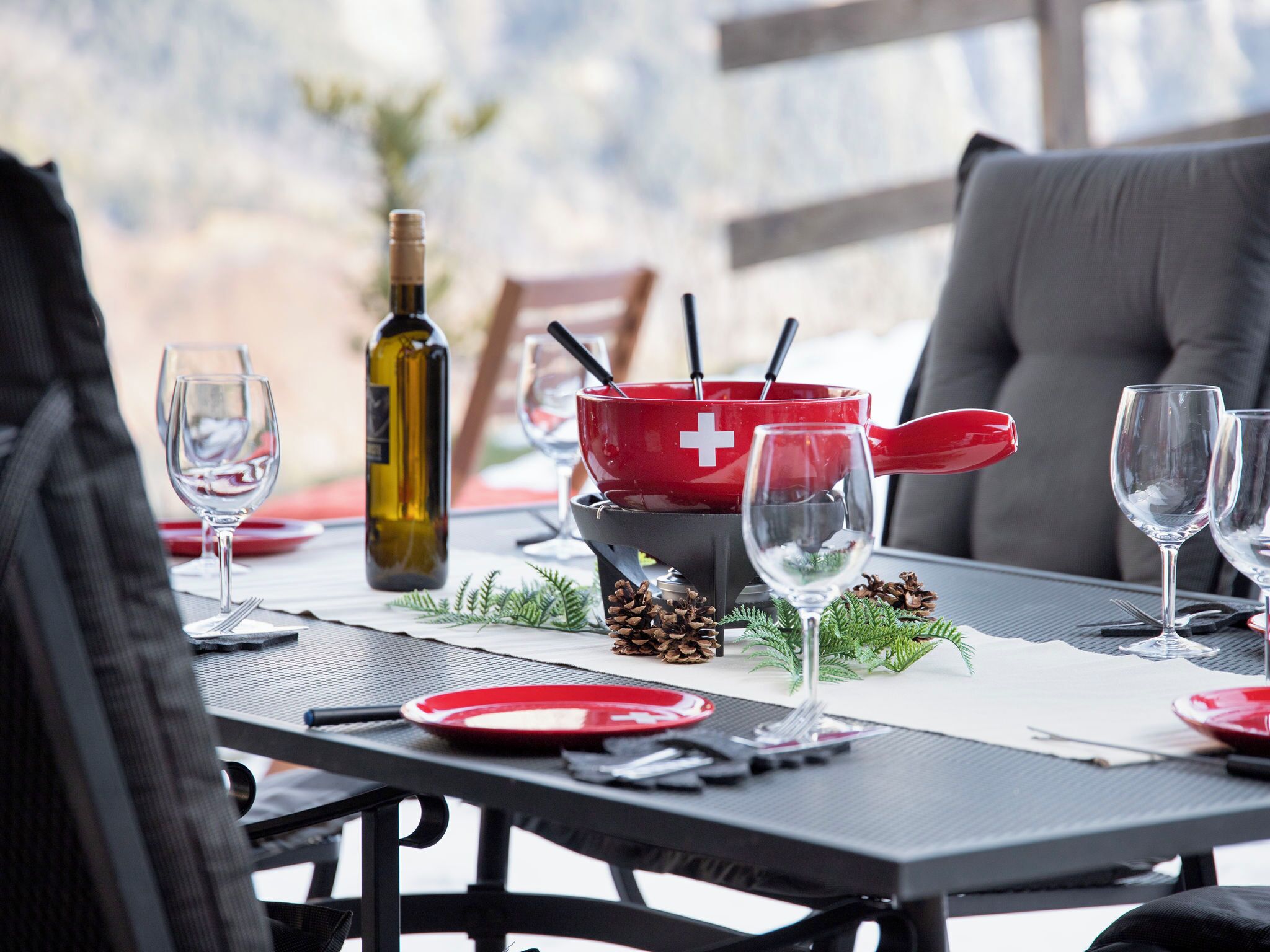 Une table à manger dressée avec des verres à vin, des assiettes et une bouteille de vin.