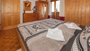 A wooden room with a bed, a dresser, and a mirror.