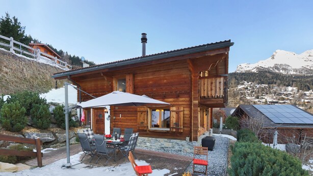 A wooden cabin with a patio, outdoor seating, and a fire pit.