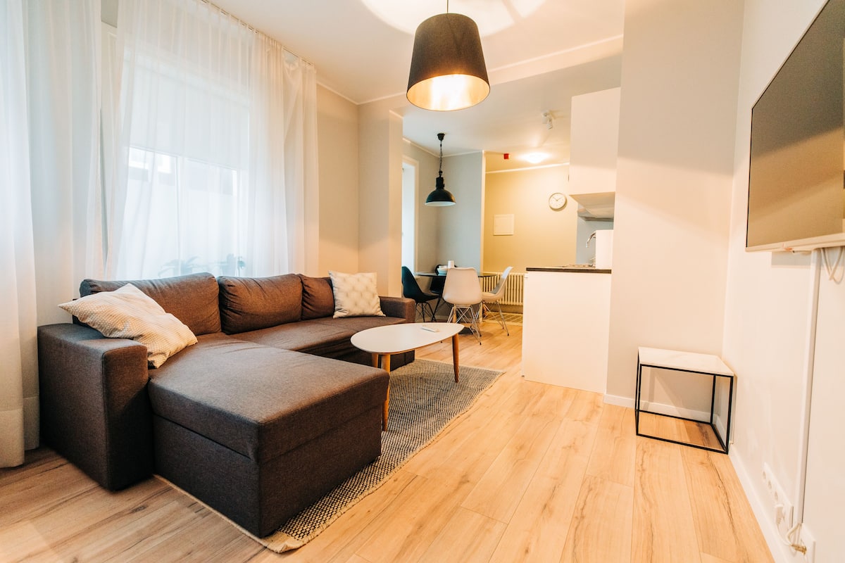 A modern living room with a sectional sofa, a small round table, and a TV stand.