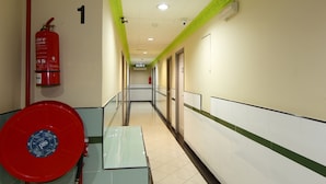 A hallway with a fire extinguisher, a number 1 sign, and a glass table. - Cosy Inn (Miri)