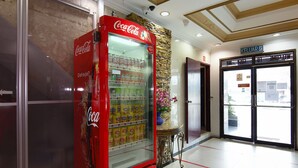A red Coca-Cola vending machine in a lobby with a stone wall and a welcome sign. - Cosy Inn (Miri)