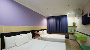 A hotel room with two beds, a small table with a vase of flowers, a green sink, and a mirror. - Cosy Inn (Miri)