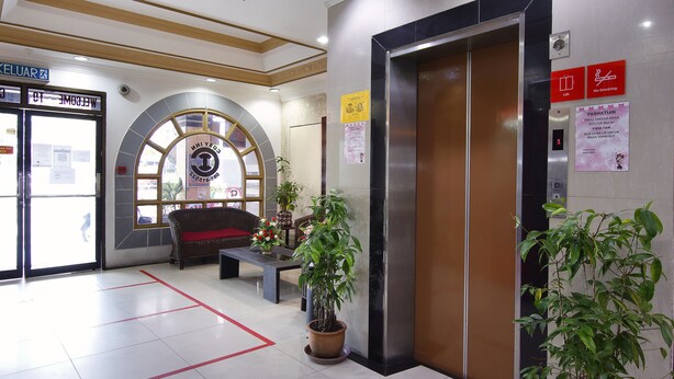 An interior with an elevator, a reception desk, and a sign indicating a smoking area. - Cosy Inn (Miri)