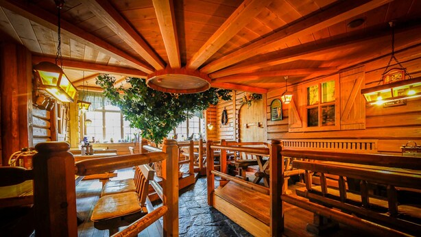 A rustic wooden interior with benches and tables, a large tree, and a stone floor. - Brewery Gasthof Zwönitz, owner Dominik Naumann - Double room (Zwönitz)
