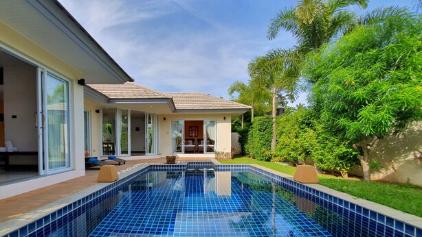 A modern house with a swimming pool, large glass doors, and a well-maintained garden.