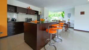 A modern kitchen with dark cabinetry, a central island, and orange bar stools.