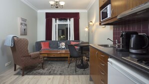 A compact living space with a kitchenette, a sofa, a dining table, and a chair.