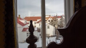 A window with a view of buildings and a snow-covered ground.