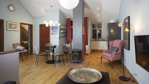 A modern living room with a dining area, a kitchen, and a seating area with a television.