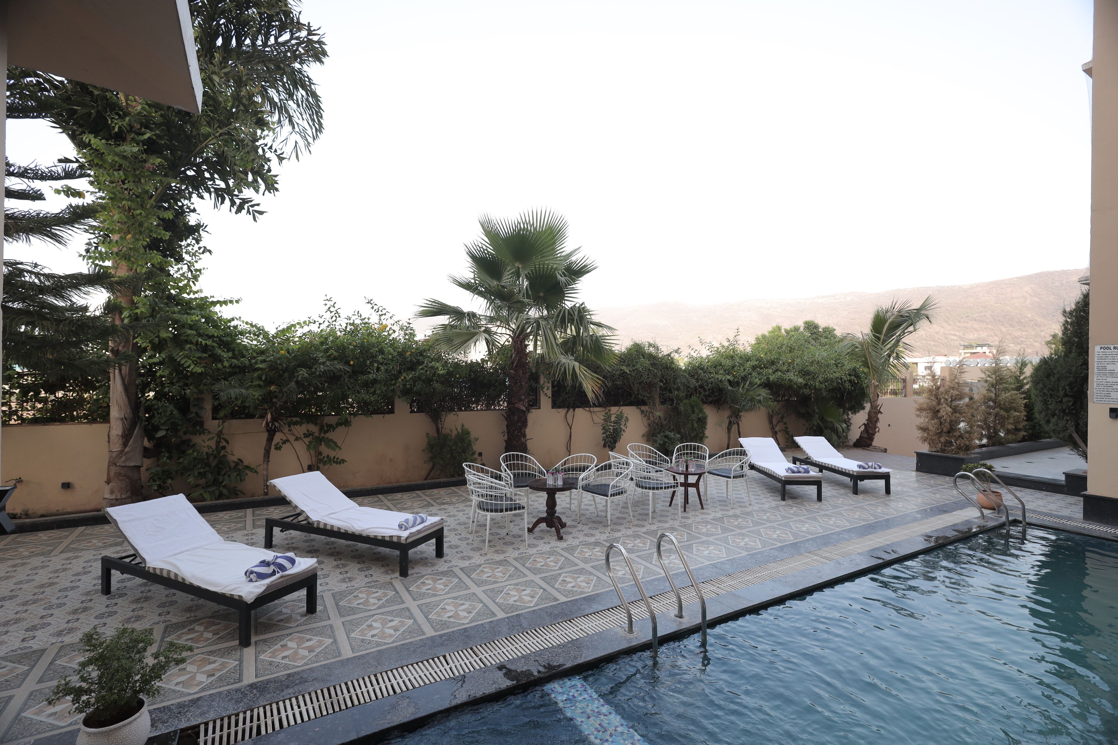 A rooftop pool area with lounge chairs, a small table, and a pool with a ladder.