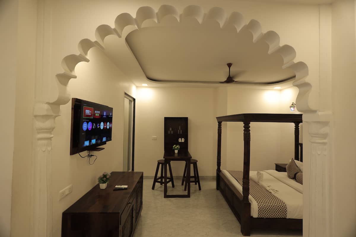 Un dormitorio con cama con dosel, un televisor montado en la pared y un pequeño escritorio con una silla.