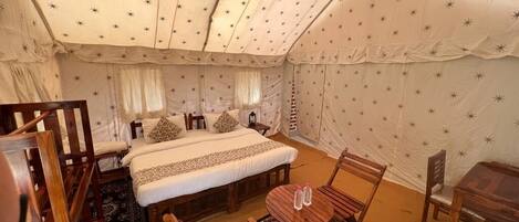 A tented room with a bed, wooden furniture, and a star-patterned ceiling.