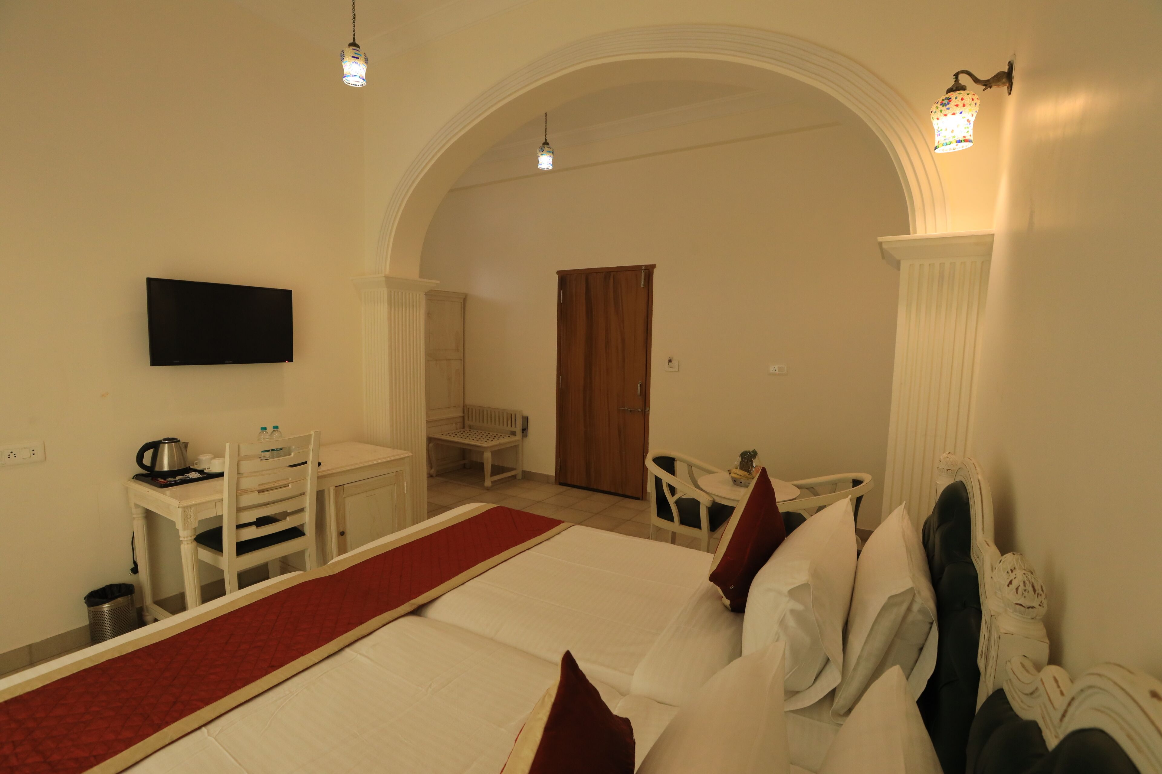 Een hotelkamer met een bed, een bureau, een stoel, een televisie en een kleine tafel.