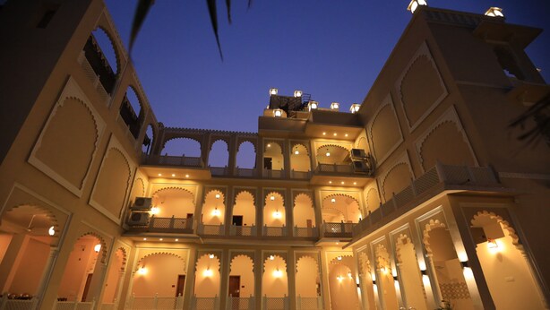 A multi-story building with arched balconies and a pool in the foreground. - Rangmahal Pushkar by DIV Hospitality (Pushkar)