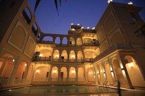 A multi-story building with arched balconies and a pool in the foreground. - Rangmahal Pushkar by DIV Hospitality (Pushkar)