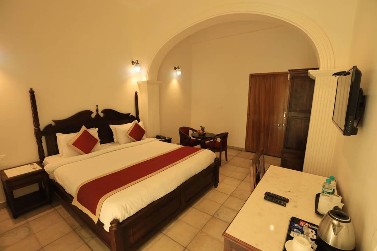 Una habitación de hotel con una cama grande, un escritorio, una silla, un televisor y un armario.