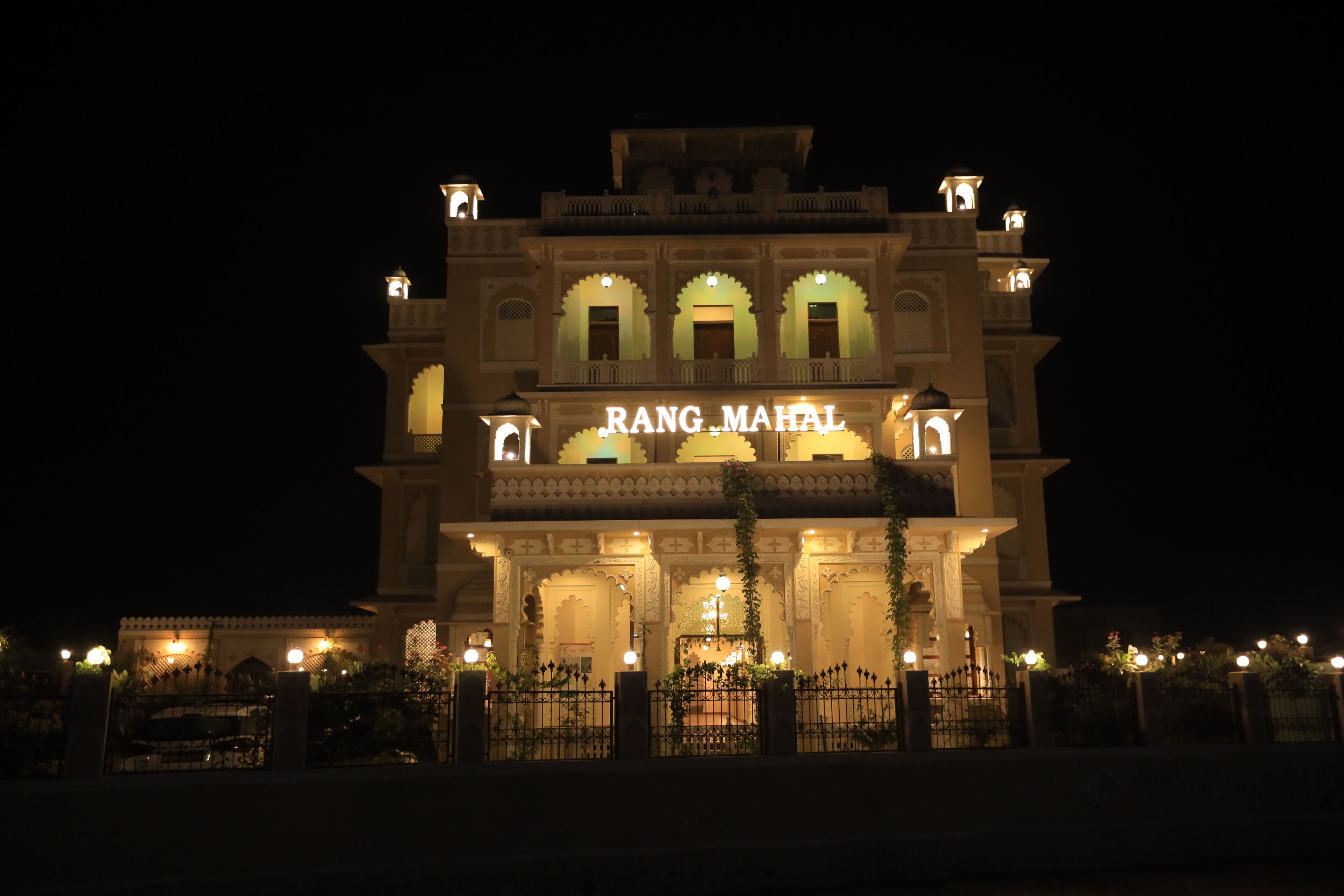 A grand building with the sign "RANG MAHAL" at night, featuring ornate arches and multiple levels.