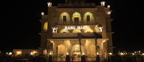 A grand building with the sign "RANG MAHAL" at night, featuring ornate arches and multiple levels.