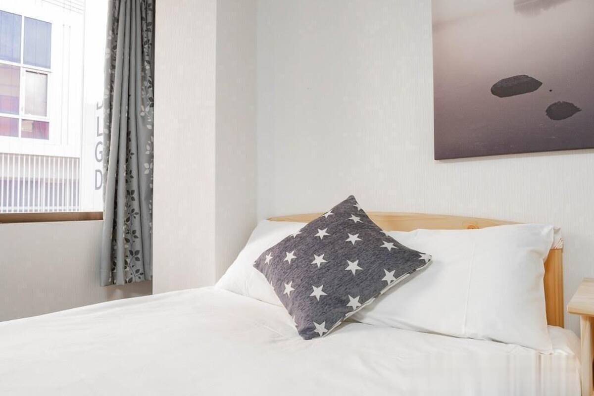 A neatly made bed with white bedding and a pillow featuring a star pattern.