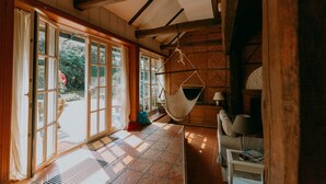 Une pièce spacieuse dotée de grandes portes-fenêtres coulissantes donnant sur un jardin, d’un fauteuil suspendu et d’une cheminée.