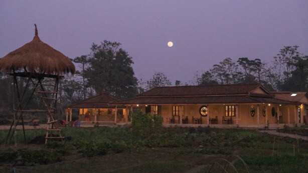 A rustic building with a thatched-roof structure and a large circular window. - Tharu Community Lodge (Kawasoti)