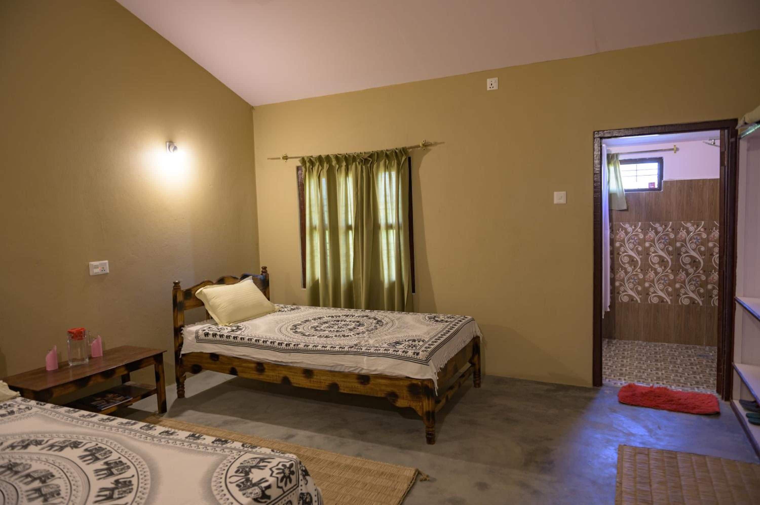 A bedroom with a single bed, a bedside table, a nightstand, and a door leading to another room.