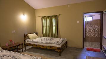 A bedroom with a single bed, a bedside table, a nightstand, and a door leading to another room.