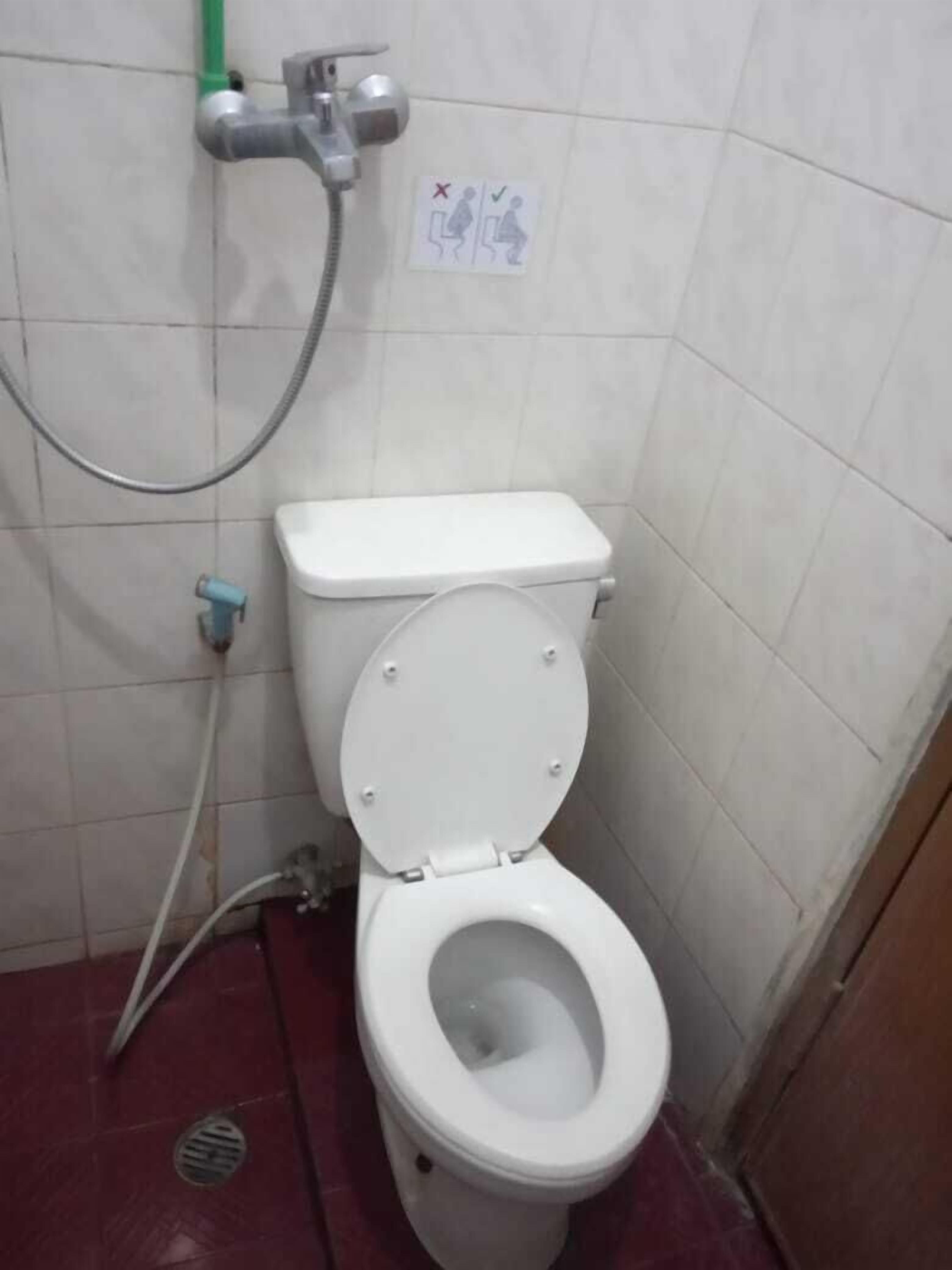 A small, basic bathroom with a toilet, a shower, and a hand dryer.