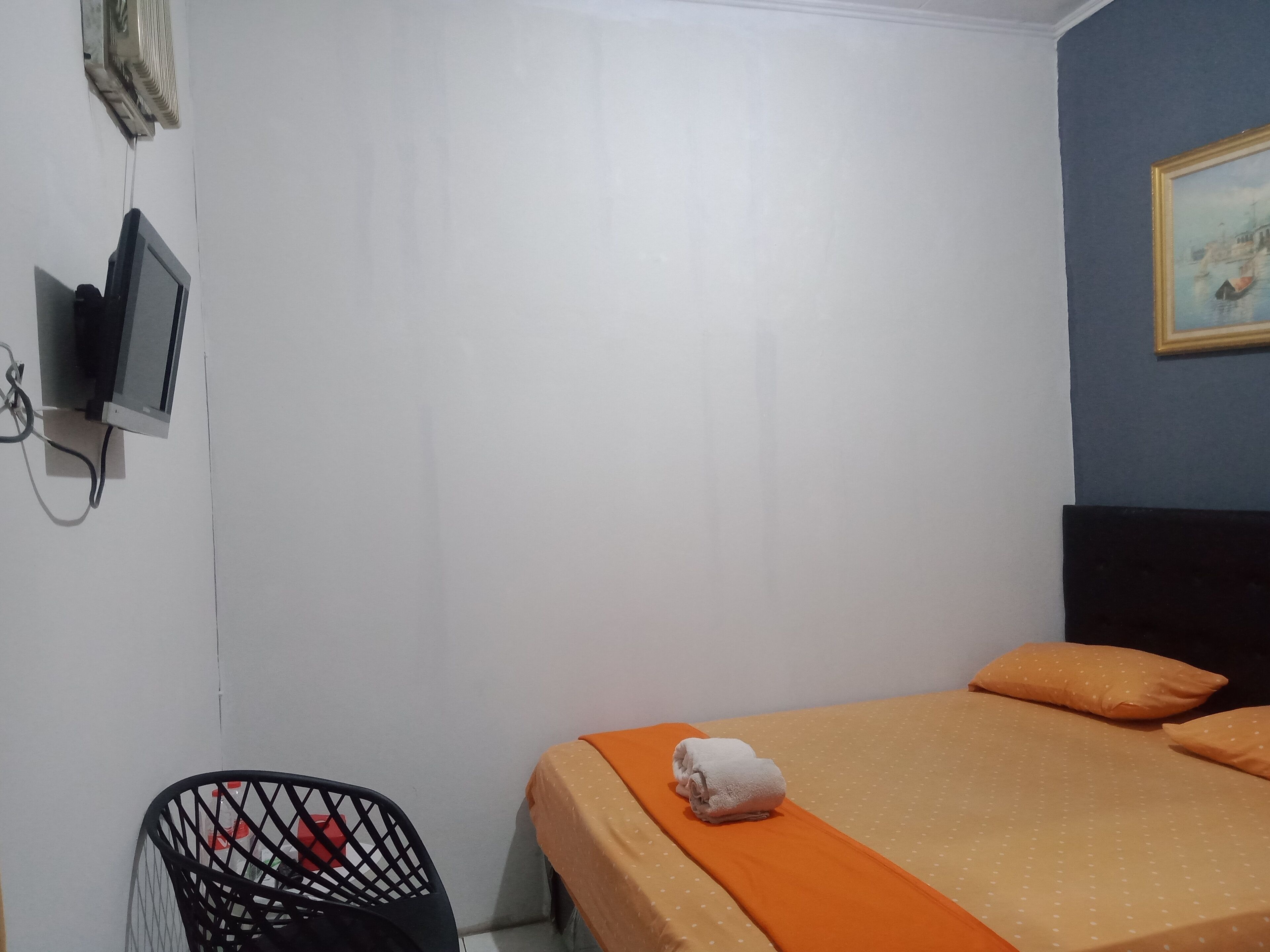 A bedroom with a bed, a TV, and a chair.