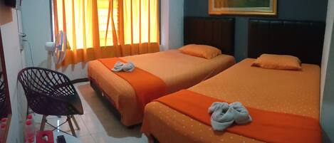 A hotel room with two beds, a chair, a small table with a remote control, and a painting on the wall.