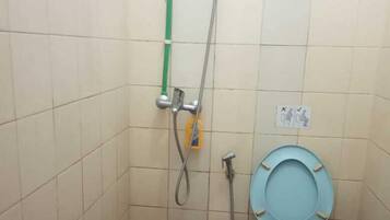 A small bathroom with a toilet, a shower, and a blue bucket.