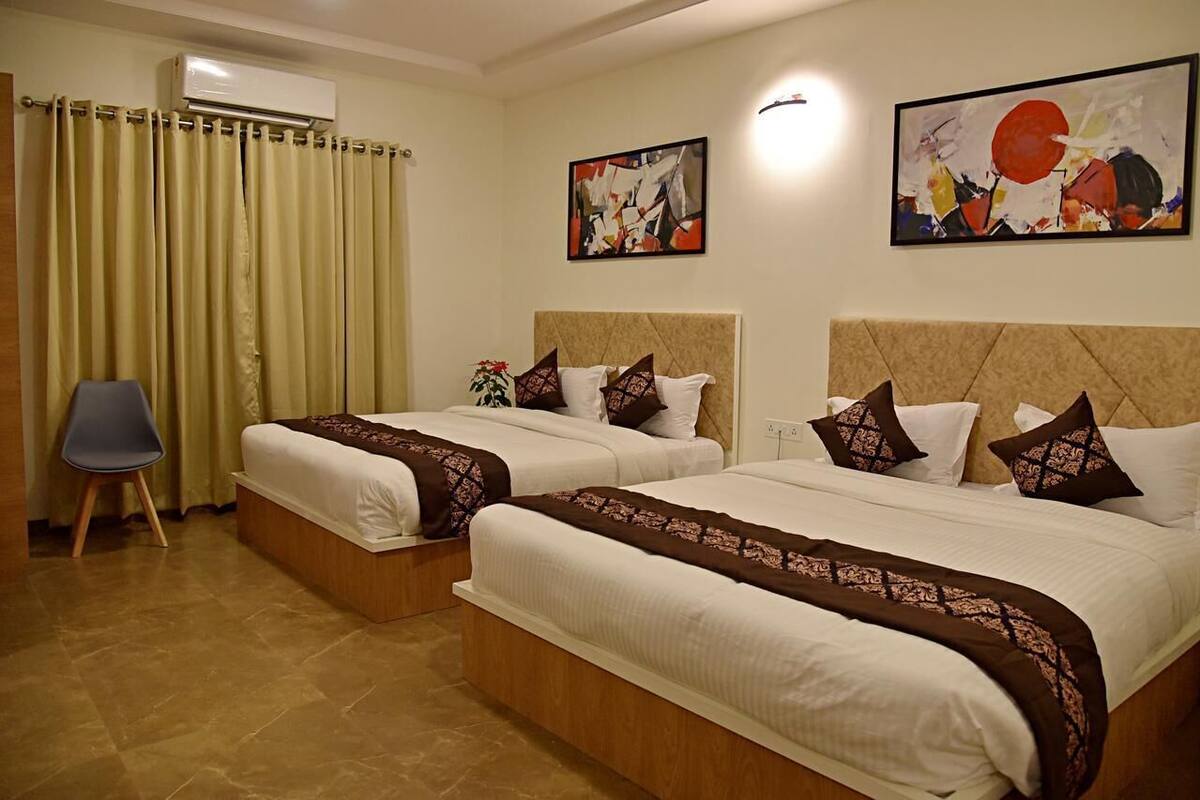 A hotel room with two beds, a chair, and artwork on the walls.