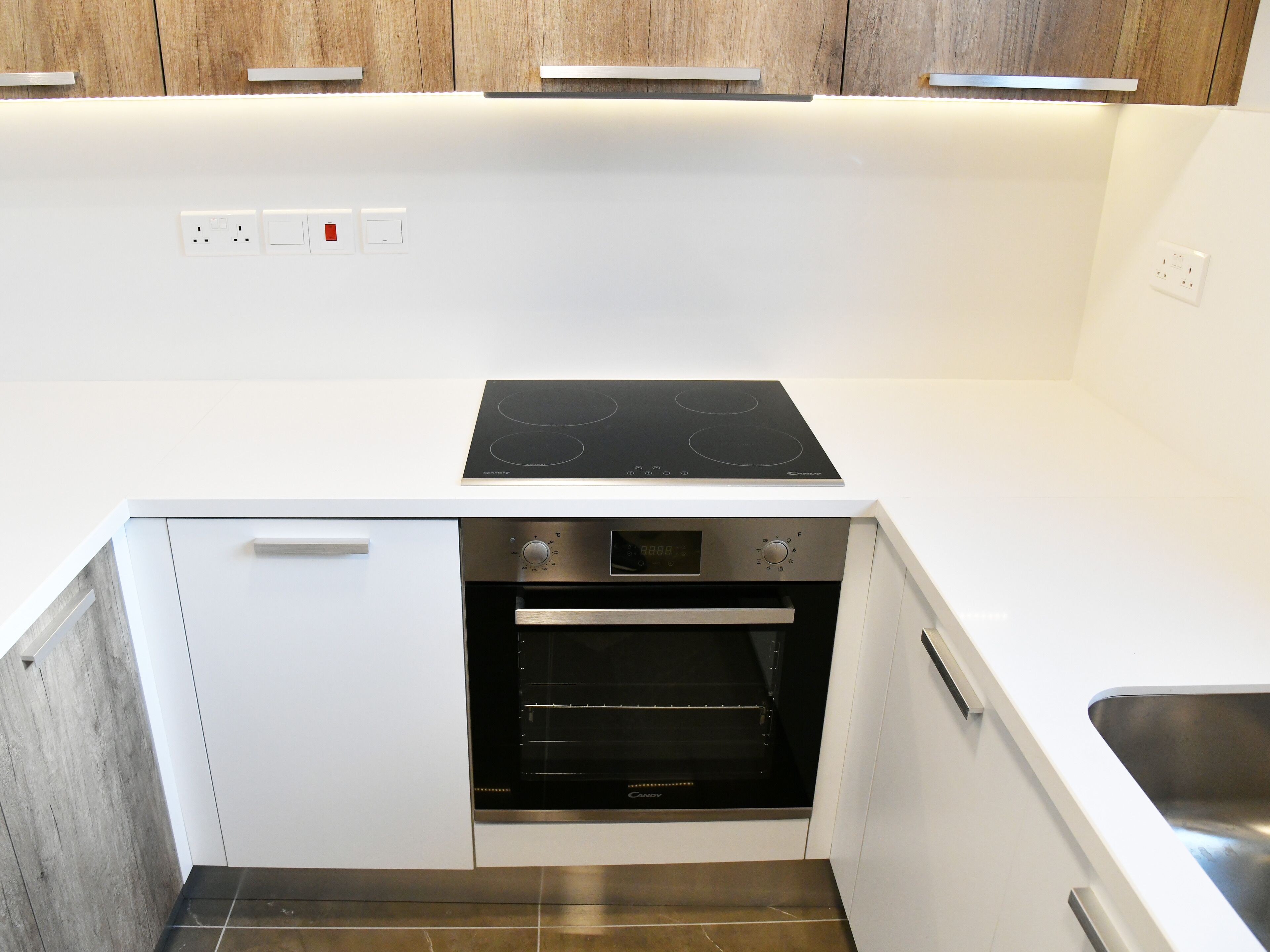 A compact kitchen with a built-in oven, a stovetop, and a sink.