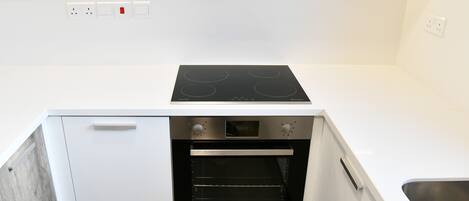 A compact kitchen with a built-in oven, a stovetop, and a sink.