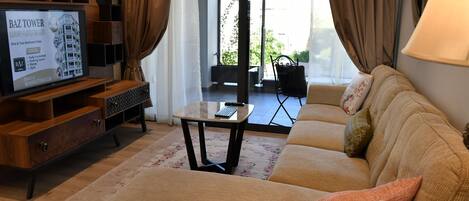 Un salón con sofá, mesa de centro y televisor mostrando un anuncio de inmuebles.