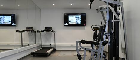 A gym with treadmills, a weight machine, and a mirrored wall.