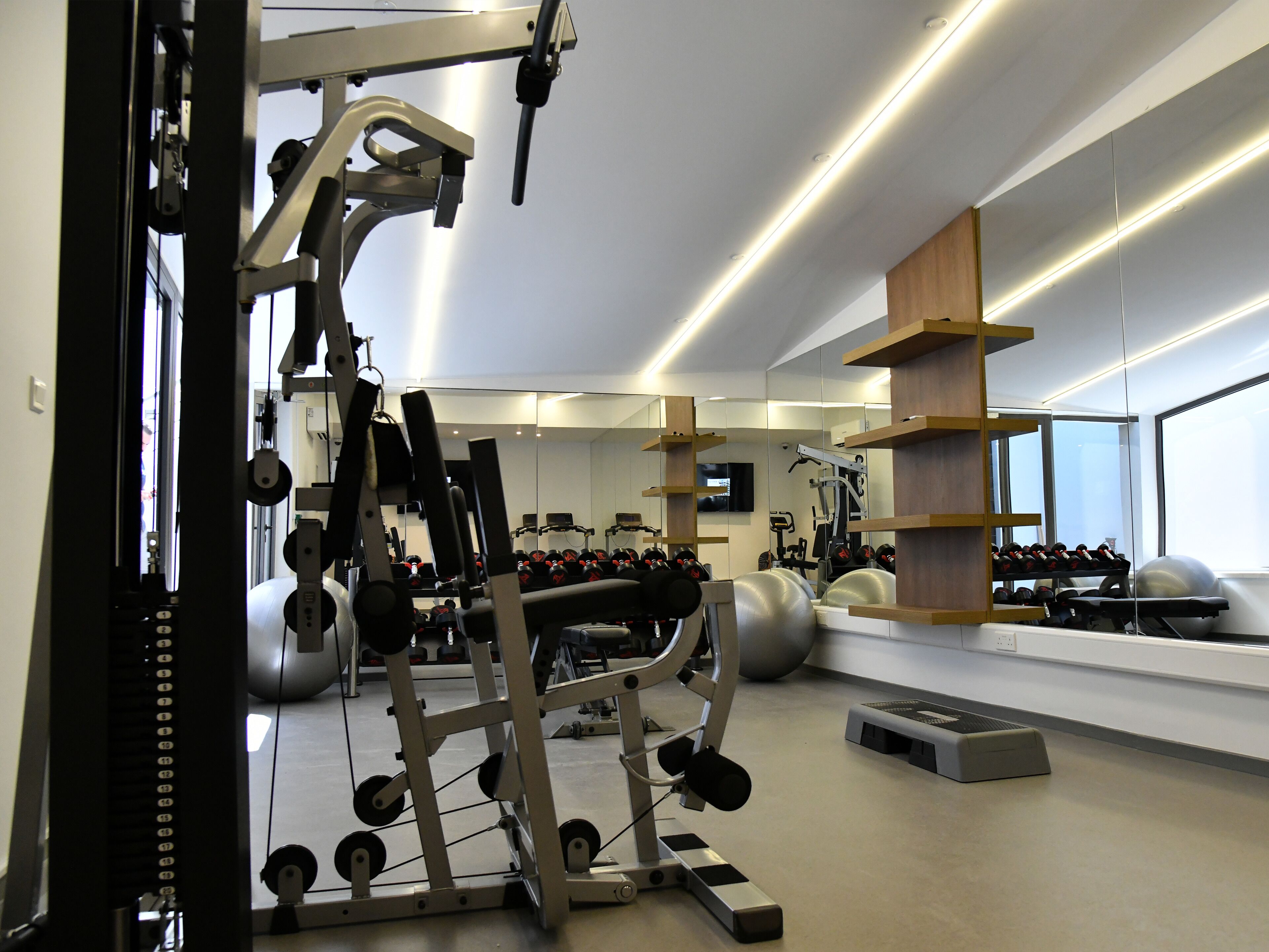Un gimnasio con equipo de ejercicio, pesas y un espejo.