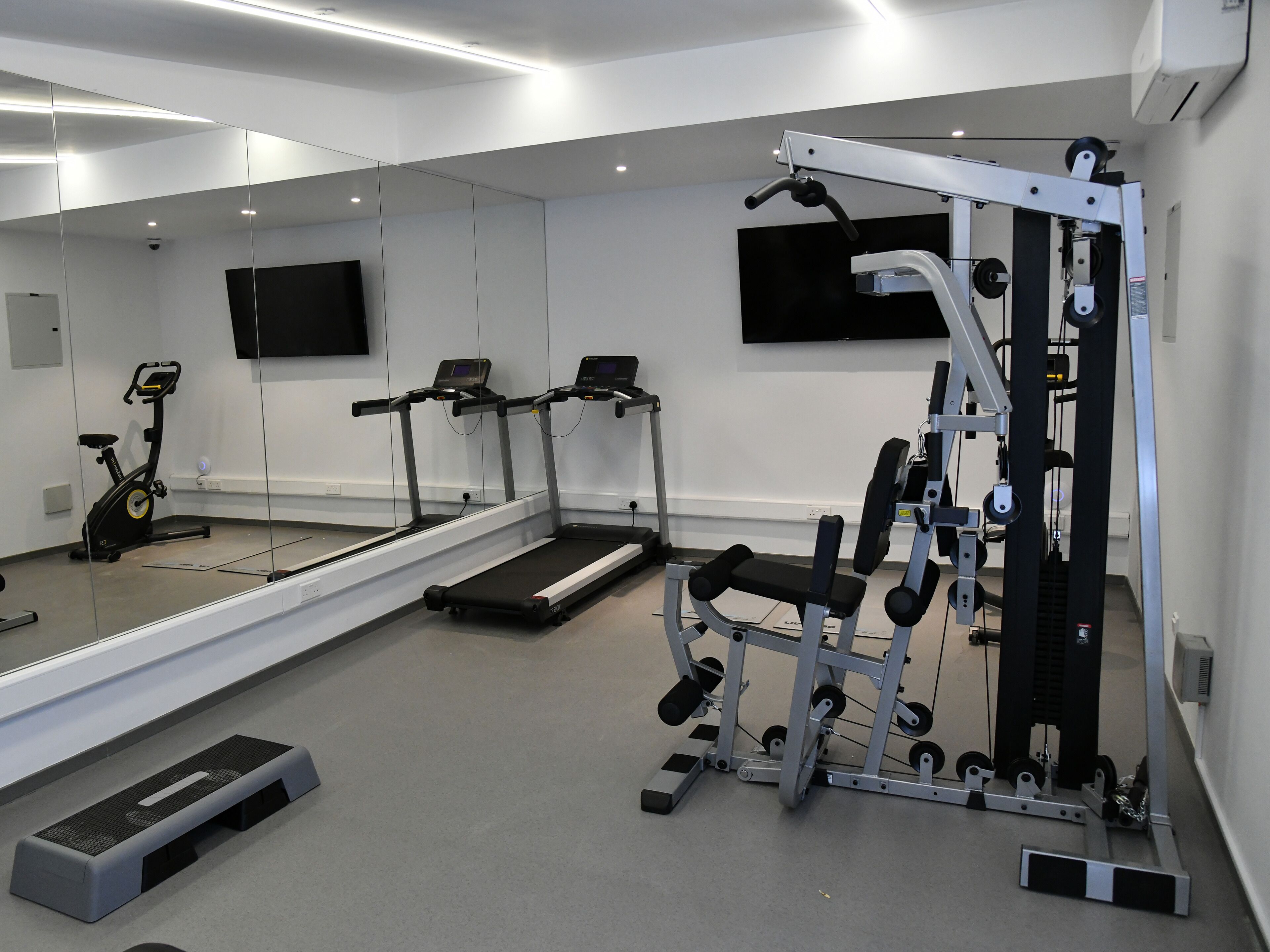 A modern gym with treadmills, an elliptical, and a weight machine.