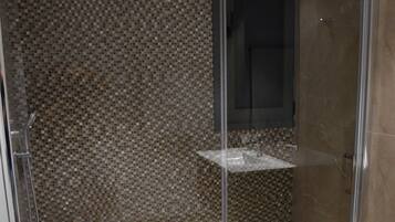 Una ducha con cerramiento de vidrio y pared de mosaicos.