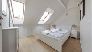 Ein Schlafzimmer mit Oberlicht, Bett, Nachttisch und Kleiderschrank.