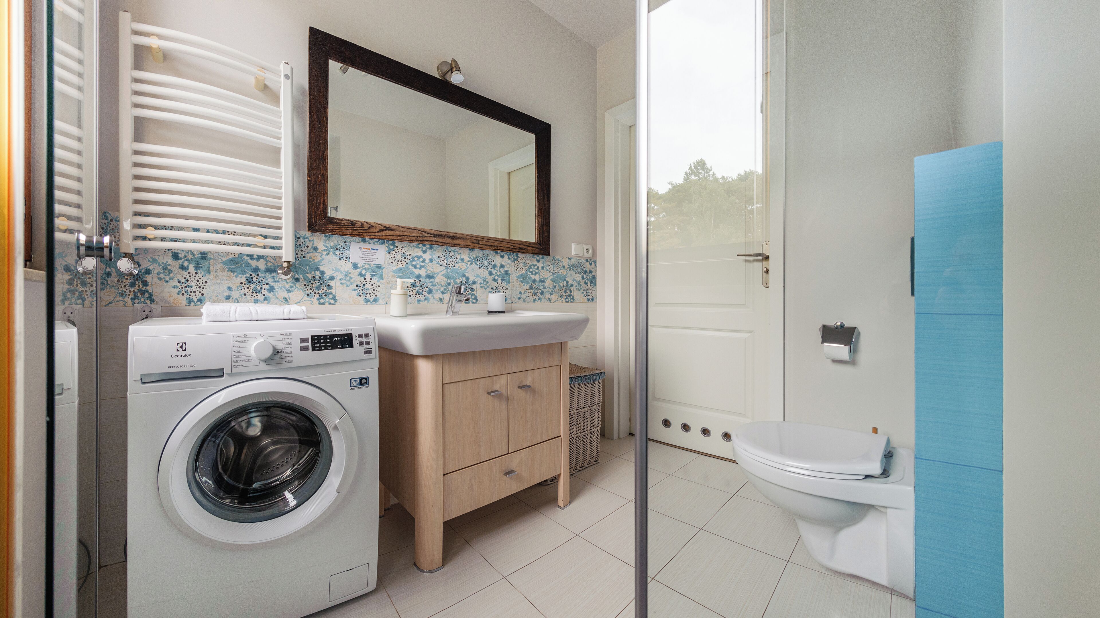 A modern bathroom with a washing machine, a sink, and a toilet.