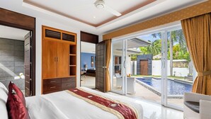 A bedroom with a large bed, a wardrobe, and a sliding glass door leading to a pool area.