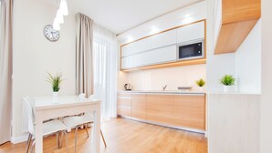 Een moderne keuken met witte kasten, een magnetron en een eethoek met een witte tafel en stoelen.