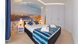 Een slaapkamer met een groot bed, nachtkastje, lamp en een kledingkast.